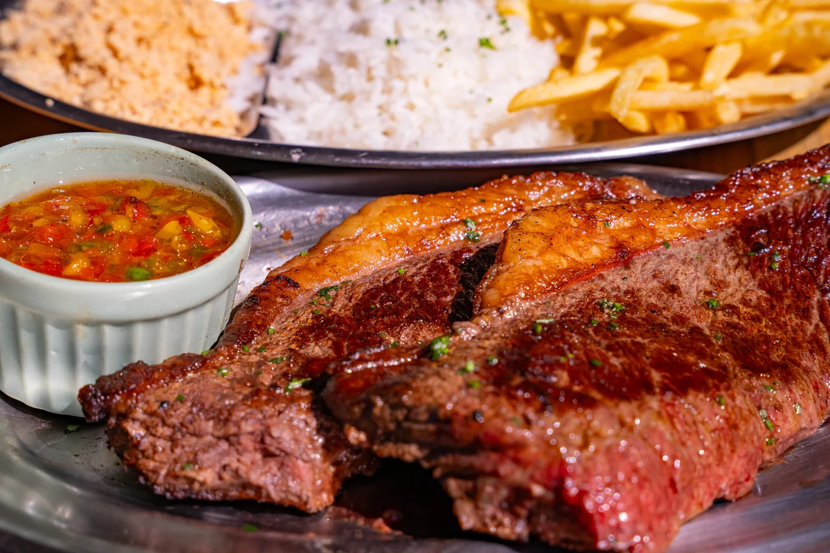 Carne grelhada com arroz, farofa e batatas no cardápio da Embaixada Carioca