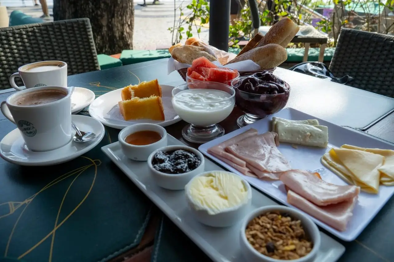 Full Embaixada Breakfast table — breads, cold cuts, açaí, yogurt and coffee with a view at Urca Hill