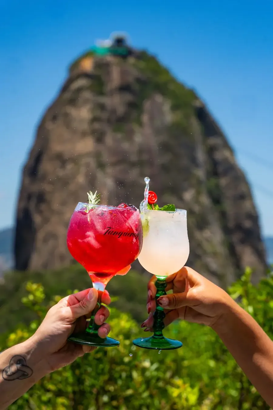 Duas taças de coquetel com Sugarloaf Mountain in the background — drinks do sunset na Embaixada Carioca, Urca Hill